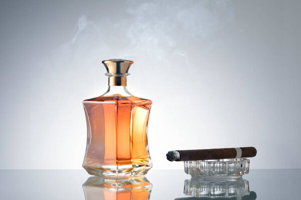 крупный план кубанской сигары и бутылки виски в сторону на серой спине. 