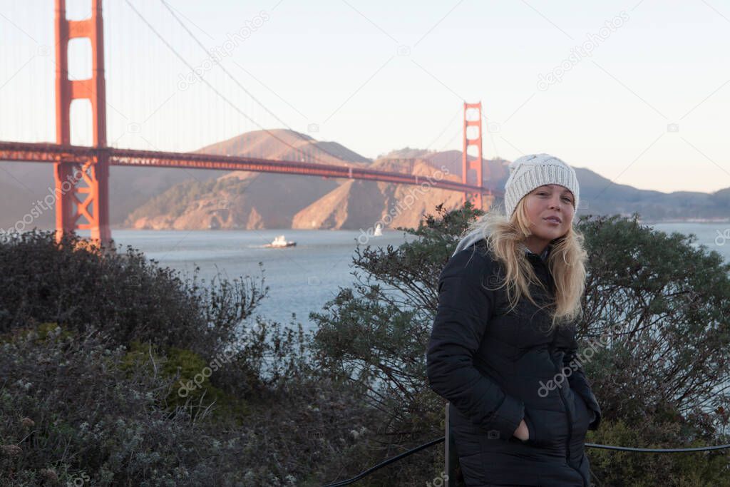 View of a young girl in black coat near golden gate in San francisco