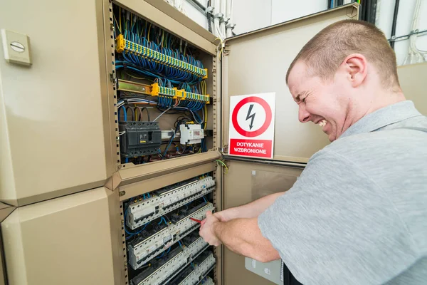 電気工事が感電します 彼の顔に苦痛の顔をしかめる — ストック写真