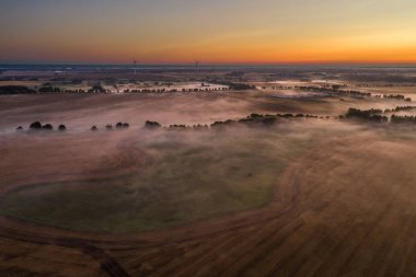 alanlarda sis, arka planda rüzgar türbinleri