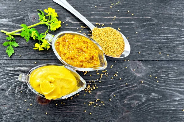 芥末酱和第戎芥末在二个玻璃锅 黄色花和种子在木板的背景从上面的勺子 — 图库照片