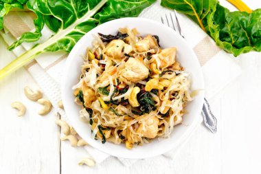 Yapraklı pancar, tavuk göğsü, kaju fıstığı ve soya sosu üstüne hafif bir ahşap tahta karşı peçeteye bir kasede Pirinç Noodle