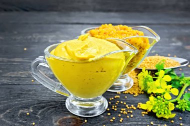 Hardal sosu ve iki cam tencere, sarı çiçek ve koyu ahşap tahta arka plan üzerine bir kaşık içinde tohum Dijon hardal