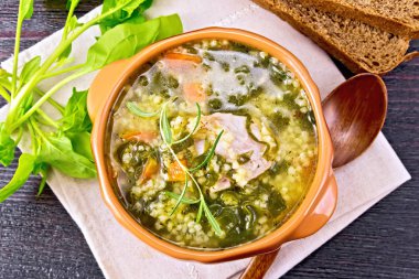 Domuz kaburga çorbası kuskus ve peçete üzerinde bir kil kase ıspanak ile yukarıdan ahşap tahta zemin üzerine ekmek