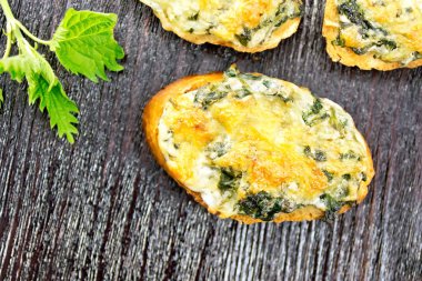 Nettles ve peynirle dilim kepekli ekmek, sarımsak ve bitkisel yağ abov bir koyu ahşap arka plan üzerinde sıcak sandviç