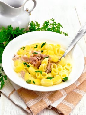 Tavuk eti, krem ve Salantro bir plaka üzerinde bir mutfak havlusu, maydanoz, ahşap tahta arka plan üzerinde metal kaşık makarna çorbası