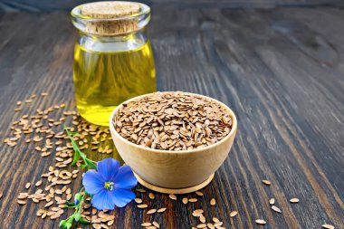 Bir kase, cam ve ahşap tahta arka plan üzerinde çiçek bezir yağı keten kahverengi tohumları