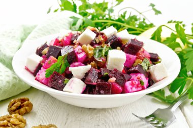 Salata kırmızı pancar, beyaz peynir, elma, ceviz, maydanoz, terbiyeli balsamik sirke ve zeytinyağı bir plaka, bir havlu bir ışık ahşap tahta arka planı