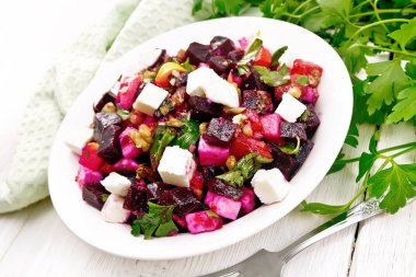 Pancar salatası, tuzlu peynir, elmalar, ceviz, maydanoz, balzamik sirke ve zeytinyağı ile tatlandırılmış bir tabak, ahşap bir tahtaya karşı peçete