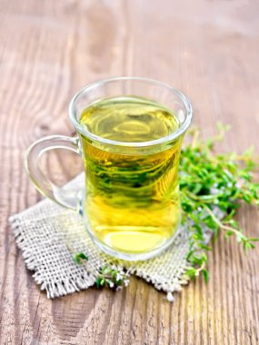 Çuval bezi peçeteye, eski bir ahşap tahta arka plan üzerinde taze kokulu bir demet kekik bir cam bardak bitkisel çay