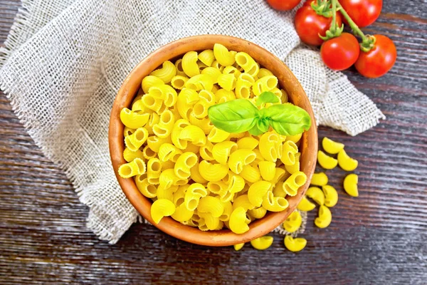 Elleboog macaroni in kom met tomaten bovenop donkere bestuur — Stockfoto