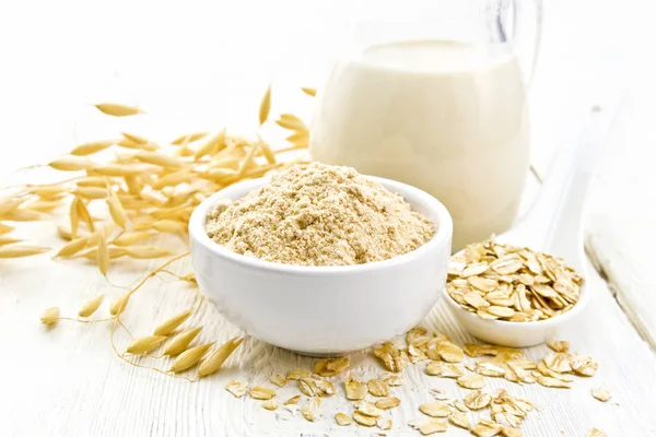 Flour oat in bowl with milk on light wooden board — Stock Photo, Image