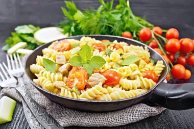 Koyu tahta üzerinde tavada tavuk ve domates ile Fusilli