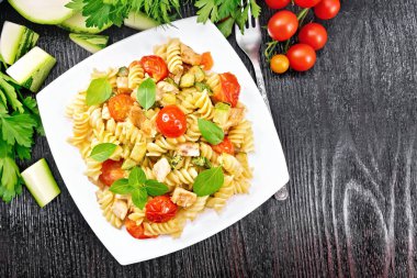 Fusilli tavuk ve domates siyah tahta üstünde plaka ile