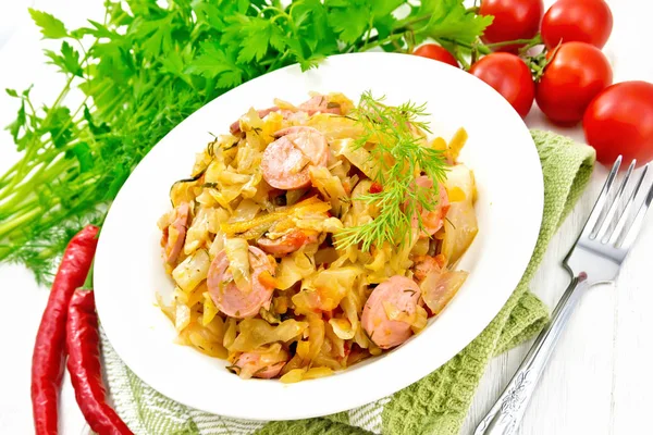 Estofado de col con salchichas en plato blanco sobre tabla ligera — Foto de Stock