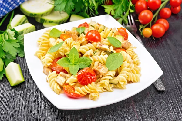 Fusilli with chicken and tomatoes in plate on board — Stock Photo, Image