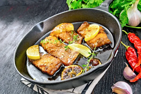 Salmon with sauce in pan on black board — Stock Photo, Image