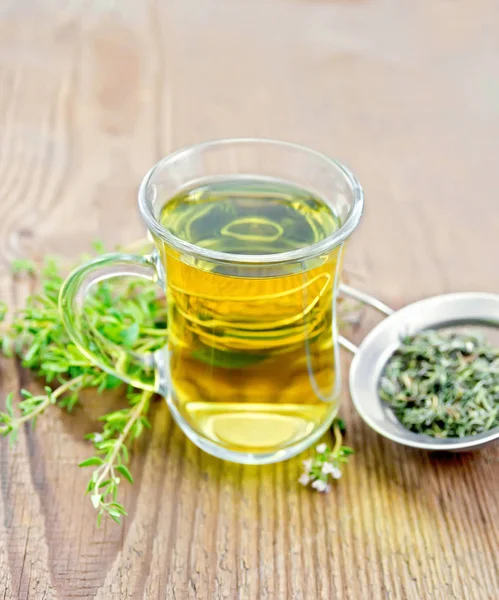 Tea of thyme in mug with strainer on old wooden board — Stock Photo, Image