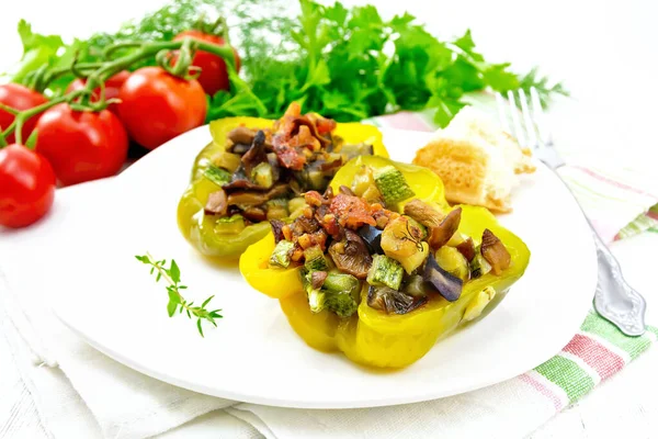 Перец фаршированный овощами в тарелке на светлой доске — стоковое фото