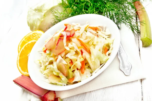 Салат из капусты и ревеня в тарелке на белой доске — стоковое фото