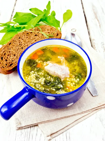 Soup with couscous and spinach in blue bowl on towel — Stock Photo, Image