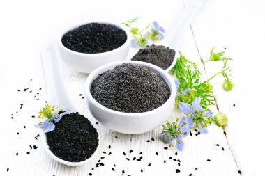 Kâselerdeki un ve oyma tohumları, mavi çiçekli kalingini dalları ve beyaz tahta arka planda yeşil yapraklar.