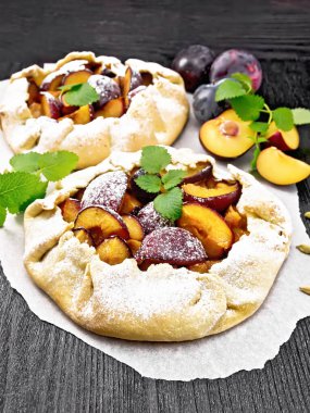 Parşömen üzerinde erik, şeker ve kakule ile iki tatlı turta, koyu ahşap arka planda yeşil nane filizi