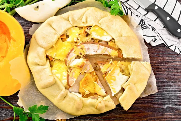 カボチャのパイ 羊皮紙に柔らかいチーズとクルミ ナプキンとナイフ 上記から木製のボードの背景にパセリ — ストック写真