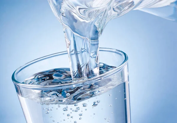 Wasser Aus Krug Glas Auf Blauem Hintergrund Gegossen — Stockfoto