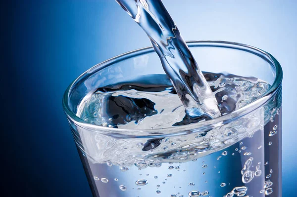 Water Gieten Glas Een Blauwe Achtergrond — Stockfoto