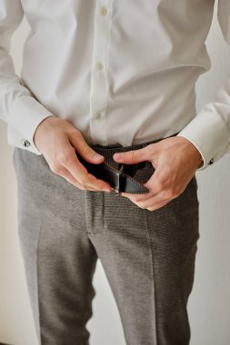 Pantolon ve unbuckling siyah deri kemer beyaz arka plan gri pantolon, beyaz gömlek unbuttoning sinek ince bir adamın görünümü kadar kapatın