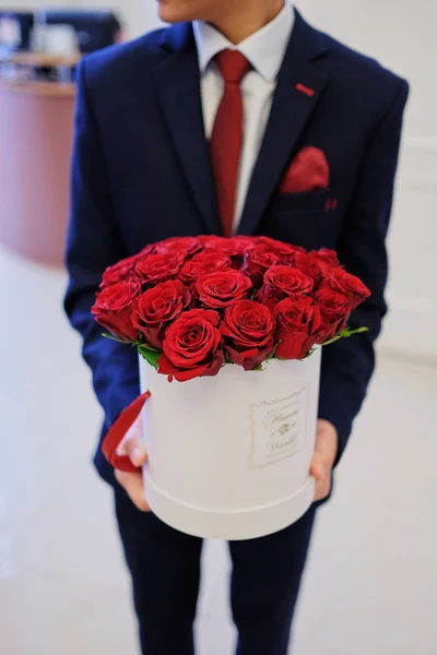 Men's hands hold a bucket of red roses in a bucket
