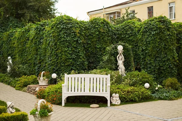 Lonely english garden bench green background behind angel sculpture