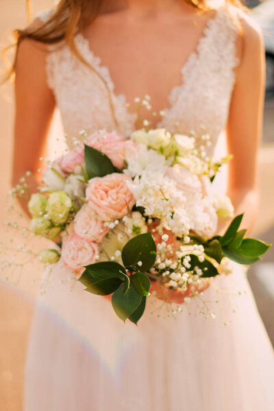 Bride holding a wedding bouquet in pastel pink colors.