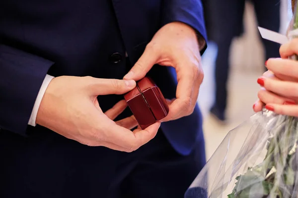 Mavi elbiseli bir adam küçük ahşap hediye kutusu alyans tutar. düğün hediyesi