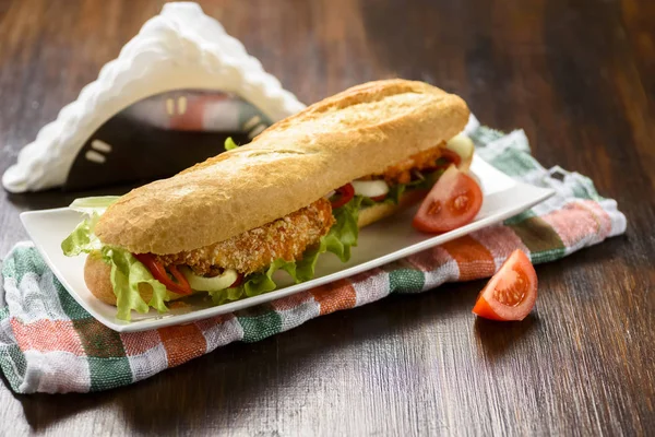 long sandwich with breaded chicken tenderloin and vegetables