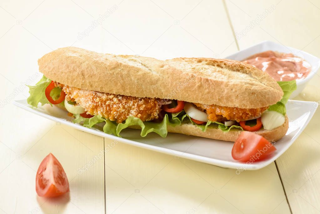 long sandwich with breaded chicken tenderloin and vegetables