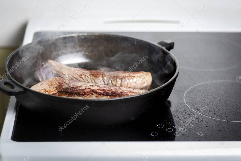 frying beef steaks on a cast iron skillet and an induction cooker