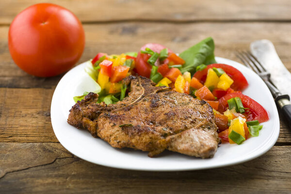 roasted pork chop with bone served with vegetables