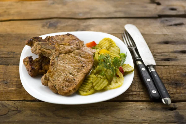 Roasted pork chop and salad of cucumbers — Stock Photo, Image