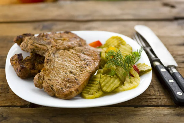 Roasted pork chop and salad of cucumbers — Stock Photo, Image