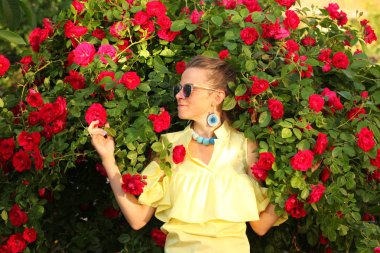 Genç güzel bir kadın kırmızı güllere karşı poz veriyor. 