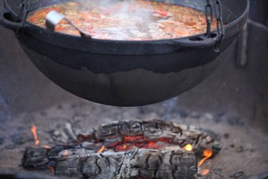 Büyük bir kazanda dışarıda ateşte yemek pişirmek.