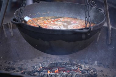 Büyük bir kazanda dışarıda ateşte yemek pişirmek.