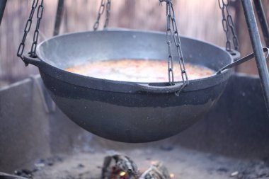Büyük bir kazanda dışarıda ateşte yemek pişirmek.