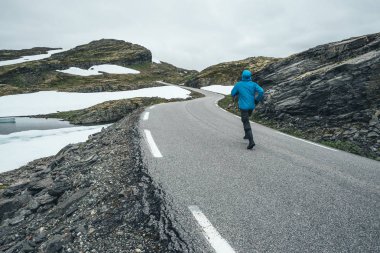Norveç doğal manzaralı rota Aurlandsfjellet. Dağ yolundan Bjorgavegen Norveç'te mavi bir ceket bir adam yürüyor
