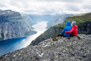 Çift kayanın üzerinde oturur ve Dağları yakınında Trolltunga bakar. Popüler turistik. Ringedalsvatnet - göl, Norveç'Hordaland Odda belediyesinde