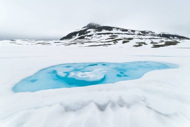 Norveç dağlarda buzlu göl manzaralı. Karlı yol bjorgavegen Norveç manzara. Turist yolu Aurlandsfjellet Aurlandsvangen Laerdalsoyri için çalışır.