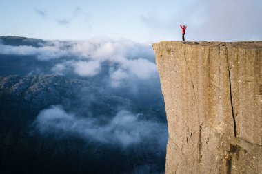 Preikestolen - Norveç'te Rock şaşırtıcı. Bulutların üstünde bir uçurumun üzerinde duran kız. Müezzin kayası, Ryfylke, en ünlü turistik Lysefjord üzerinde kuleleri