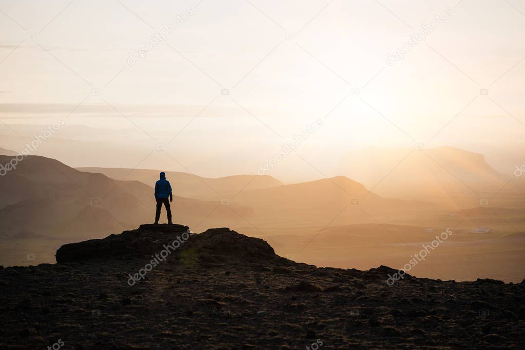 Guy meets the sunrise on the top of the mountain. Natural background with space for text